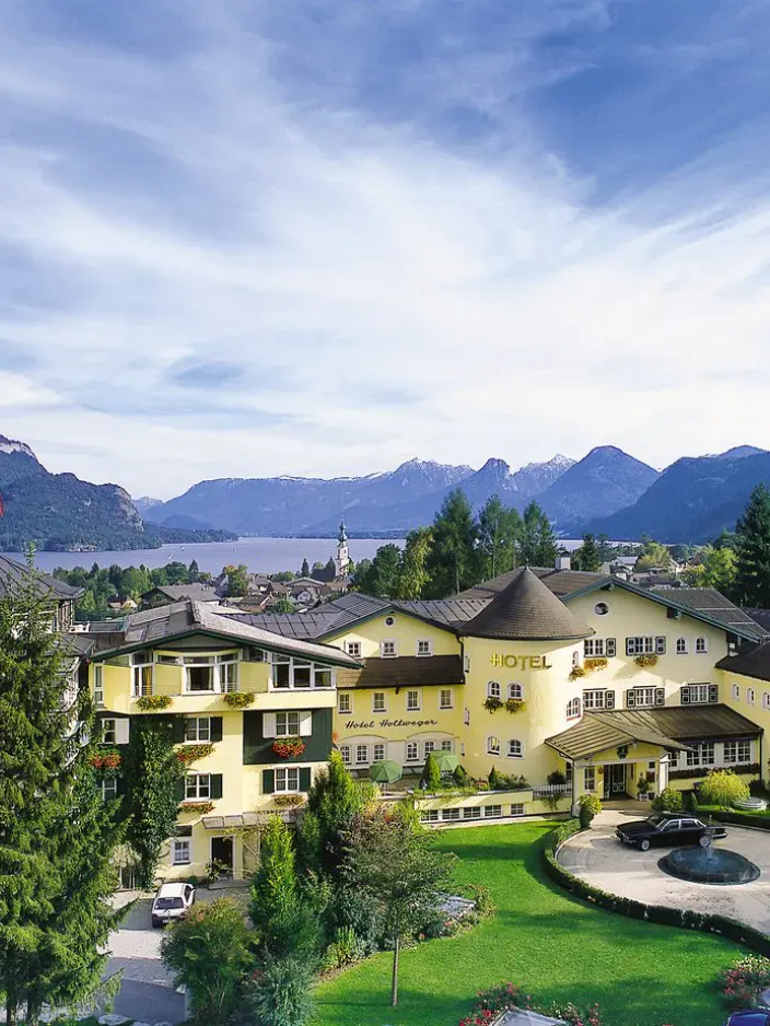 Aussenansicht des Hotels Hollweger mit Wolfgangsee und Bergen im Hintergrund