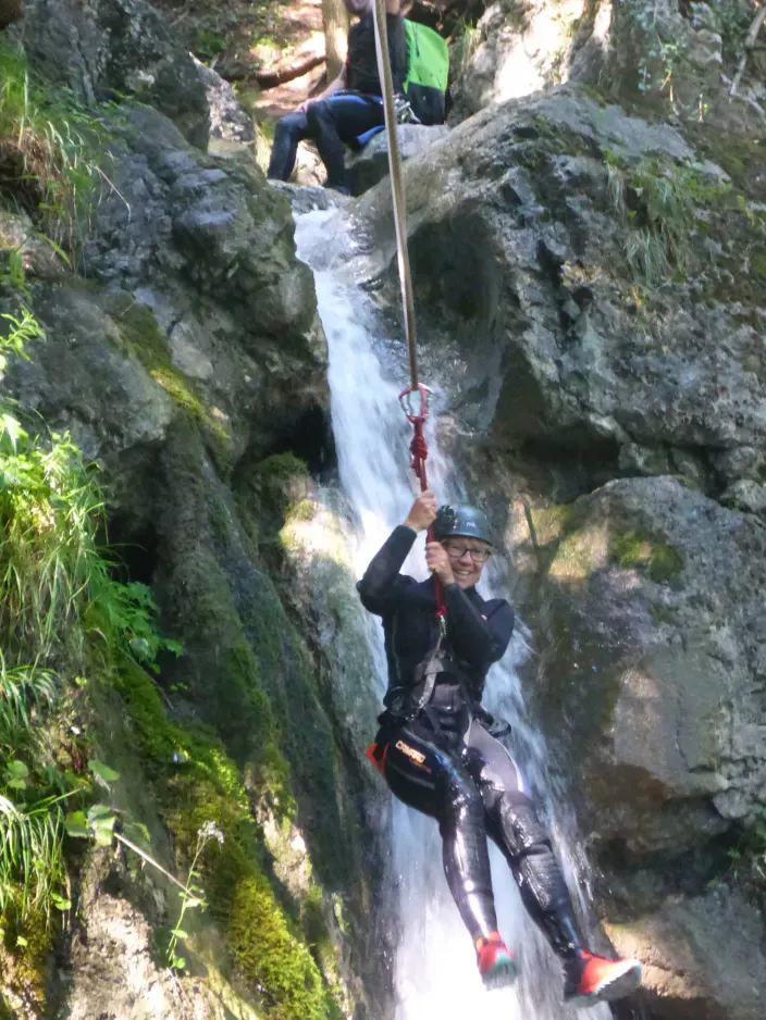 Eine Person hängt vor einem Wasserfall.