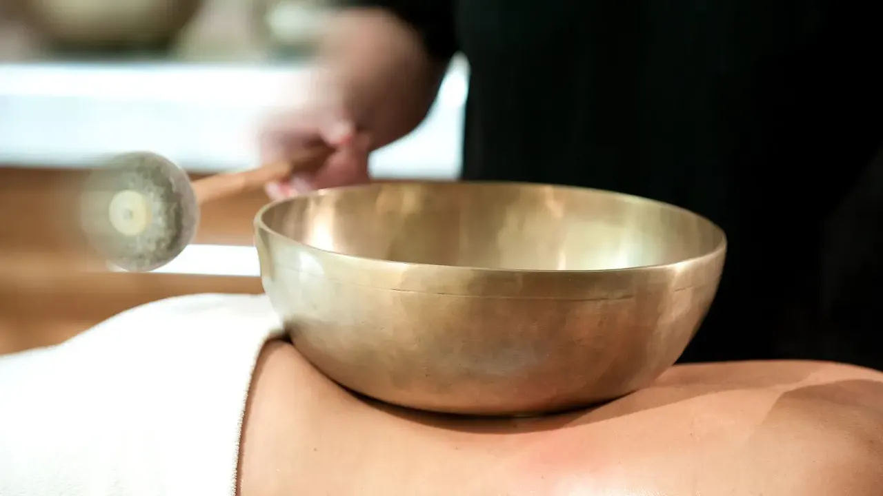 Ein Gast bei einer Klangschalenbehandlung im Wellnessbereich des Impuls Hotels Tirol