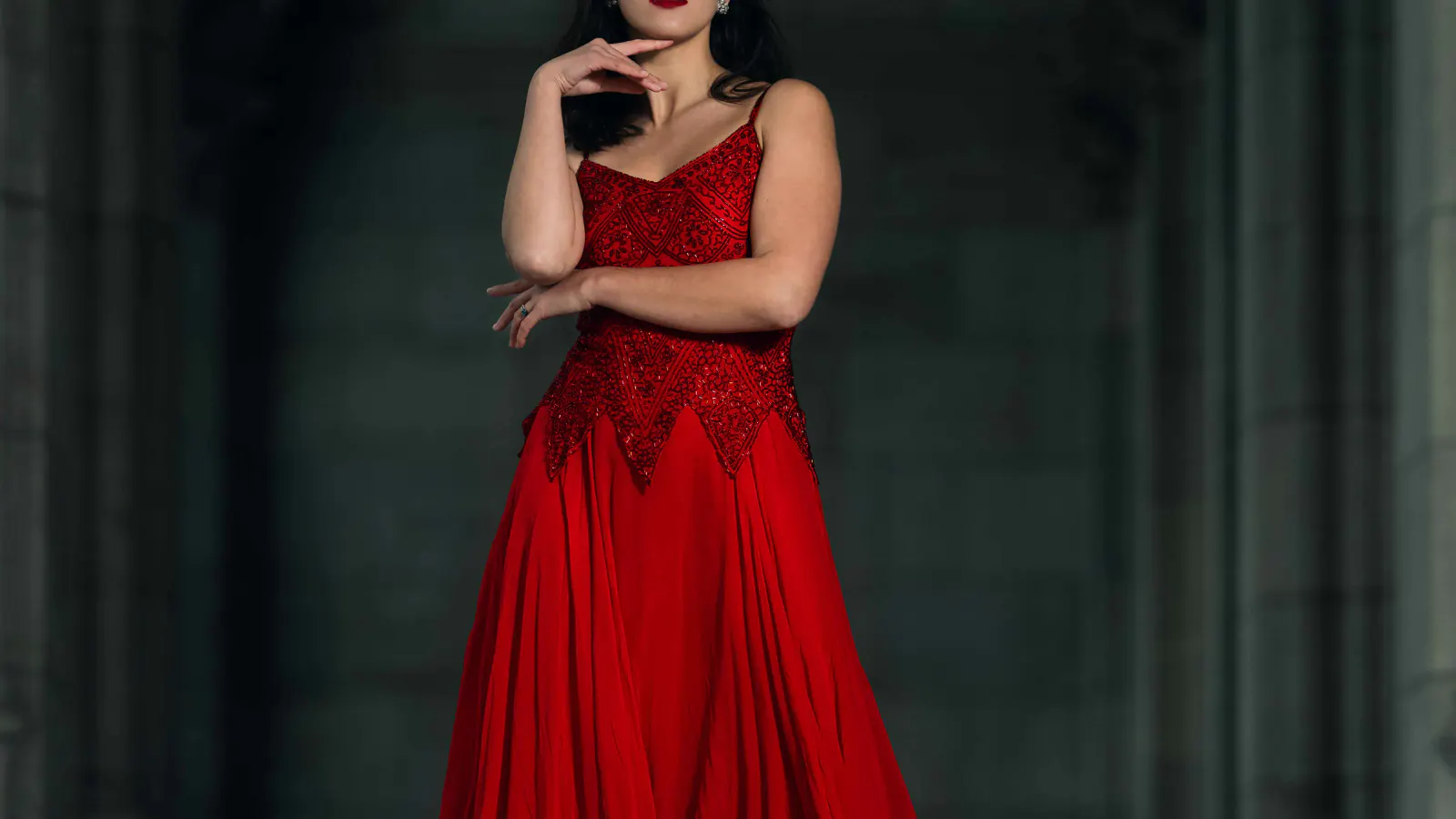 Frau im roten Kleid in dunkler architektonischer Umgebung bei einem inszenierten Editorial-Fotoshooting.