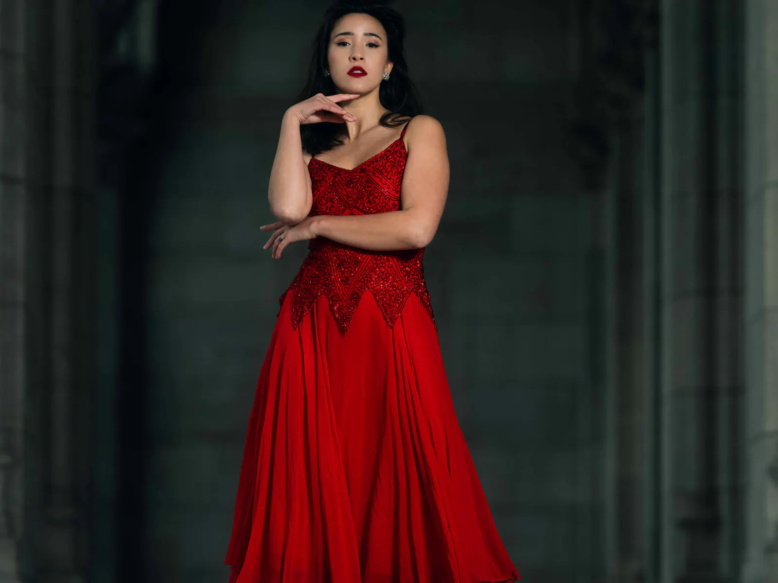 Frau im roten Kleid in dunkler architektonischer Umgebung bei einem inszenierten Editorial-Fotoshooting.