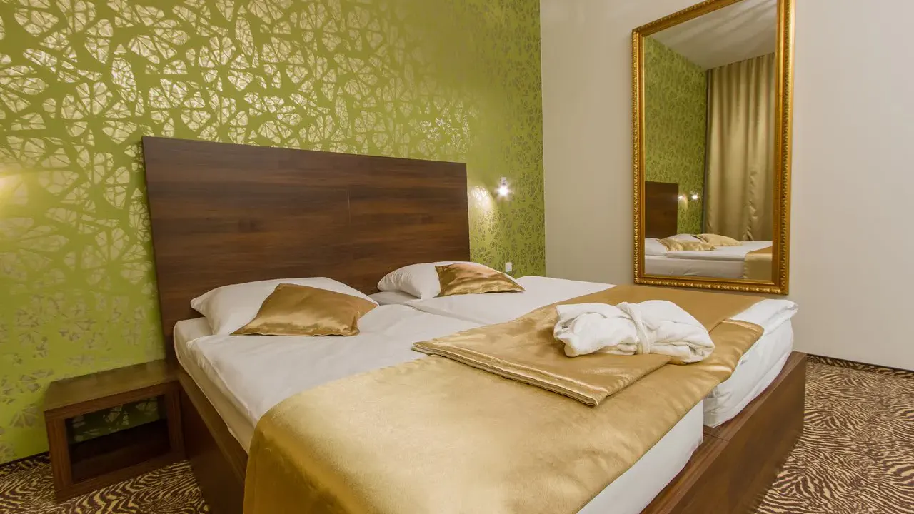 Doppelzimmer mit goldenen Akzenten und hellgrüner Tapete im Rimske Terme Hotel Rimski dvor