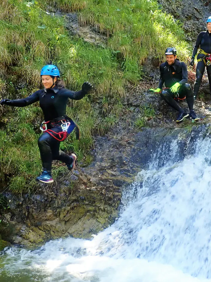 Eine Canyonautin bei einem Sprung über einen Wasserfall.
