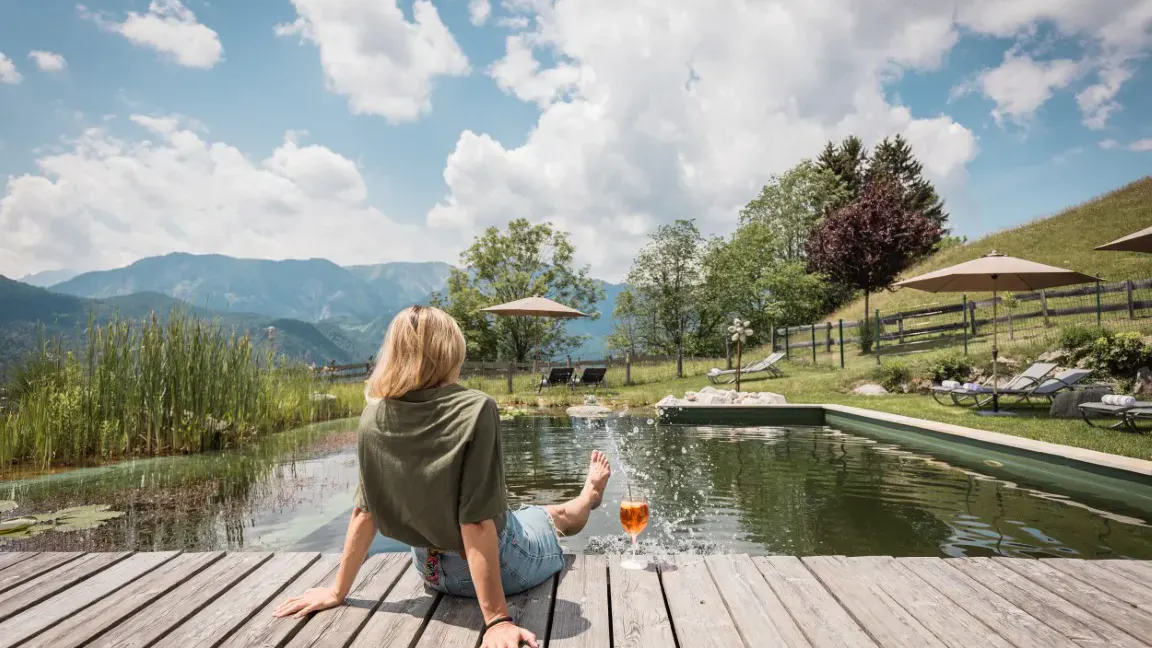 Eine Dame sitzt am Schwimmteich des Naturhotels Landhof Irschen