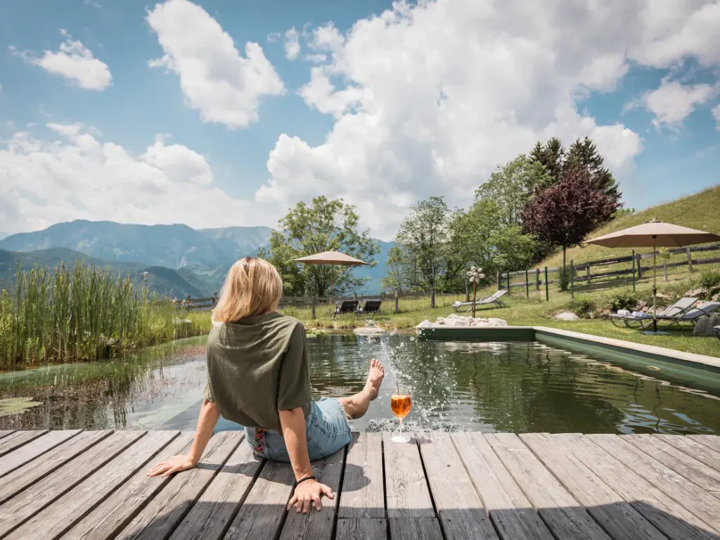 Eine Dame sitzt am Schwimmteich des Naturhotels Landhof Irschen