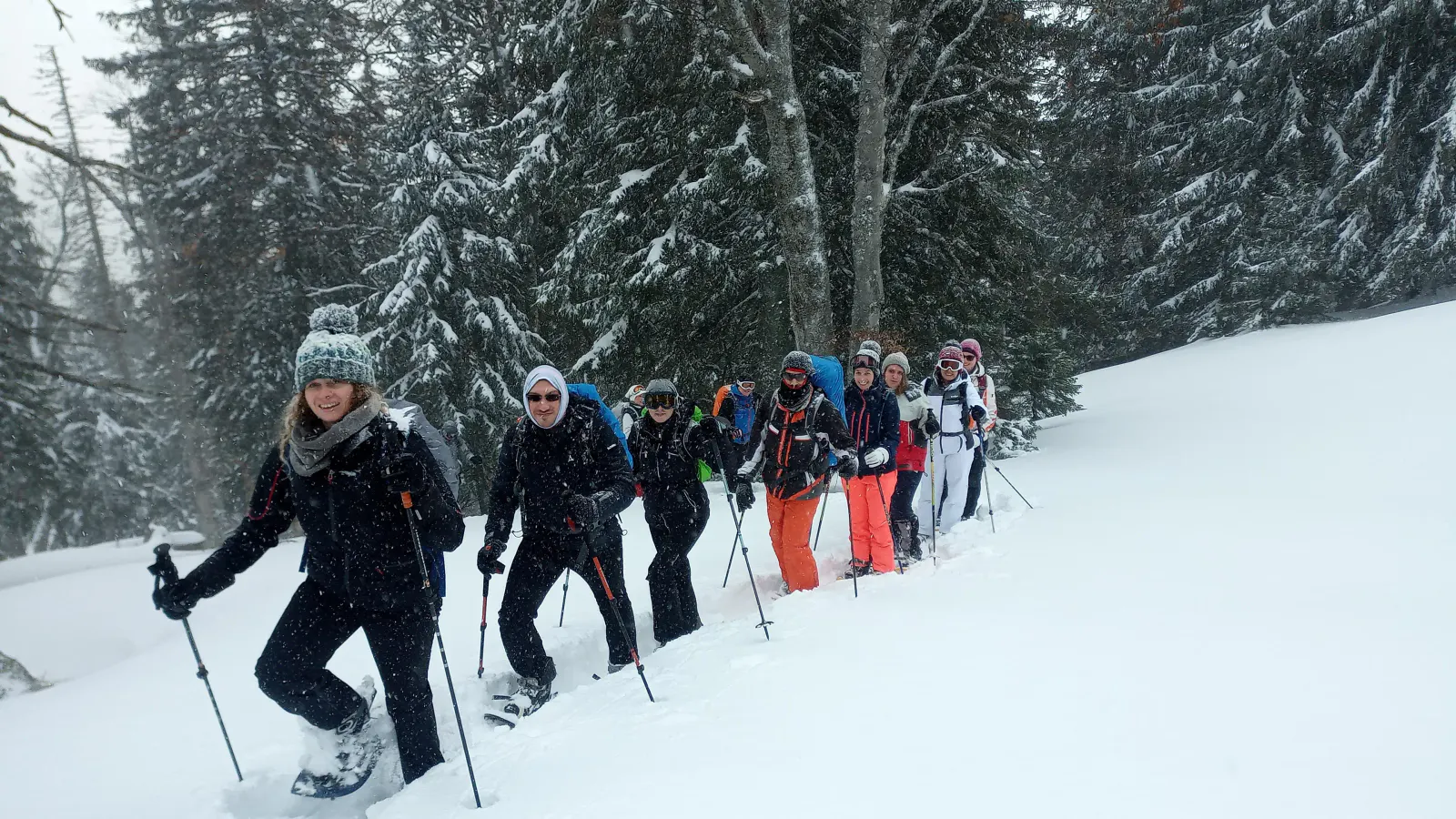 Eine Gruppe beim Schneeschuhwandern während es schneit