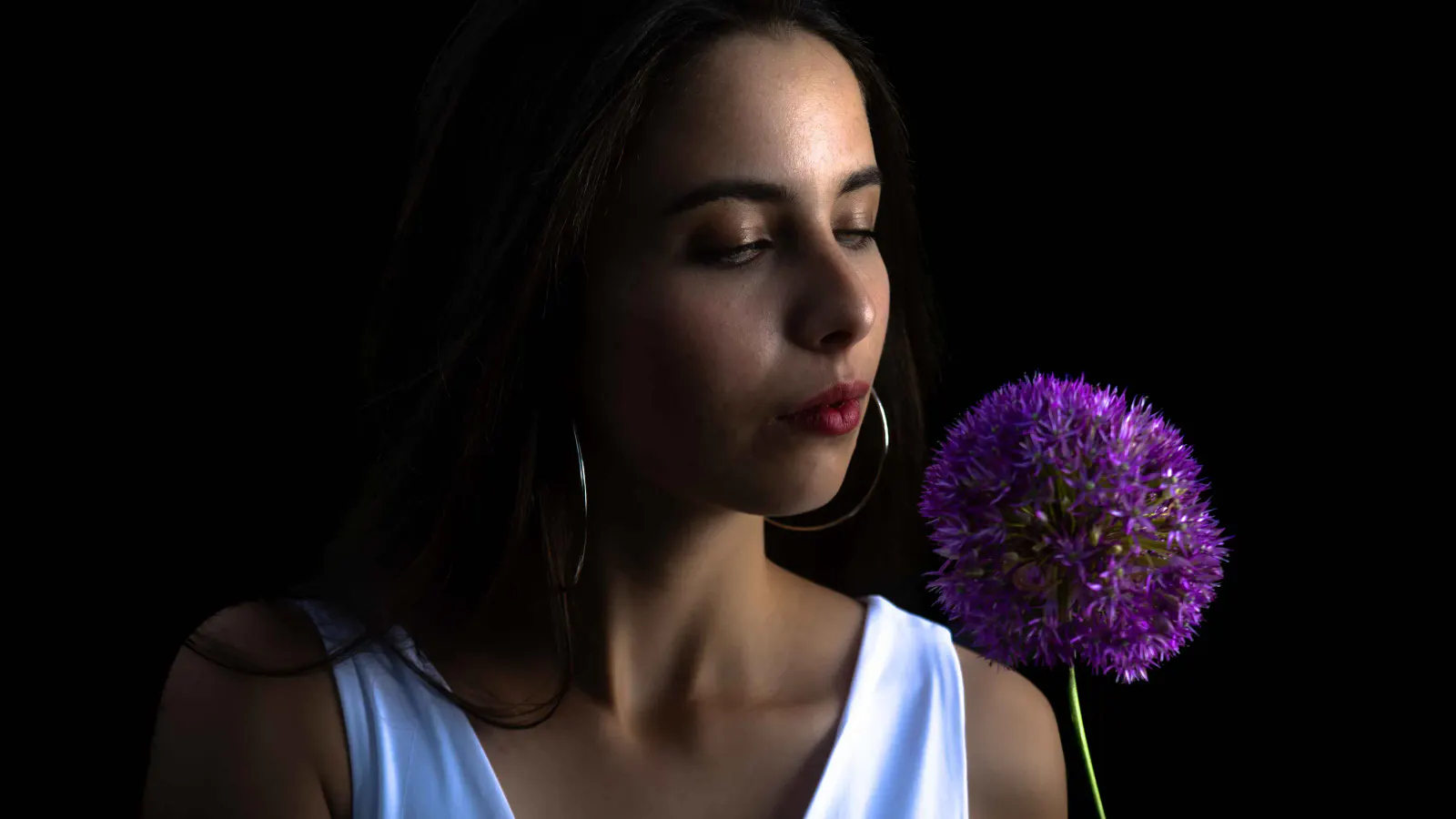 Frau mit violetter Blüte in einer dunkel inszenierten nächtlichen Portraitaufnahme.