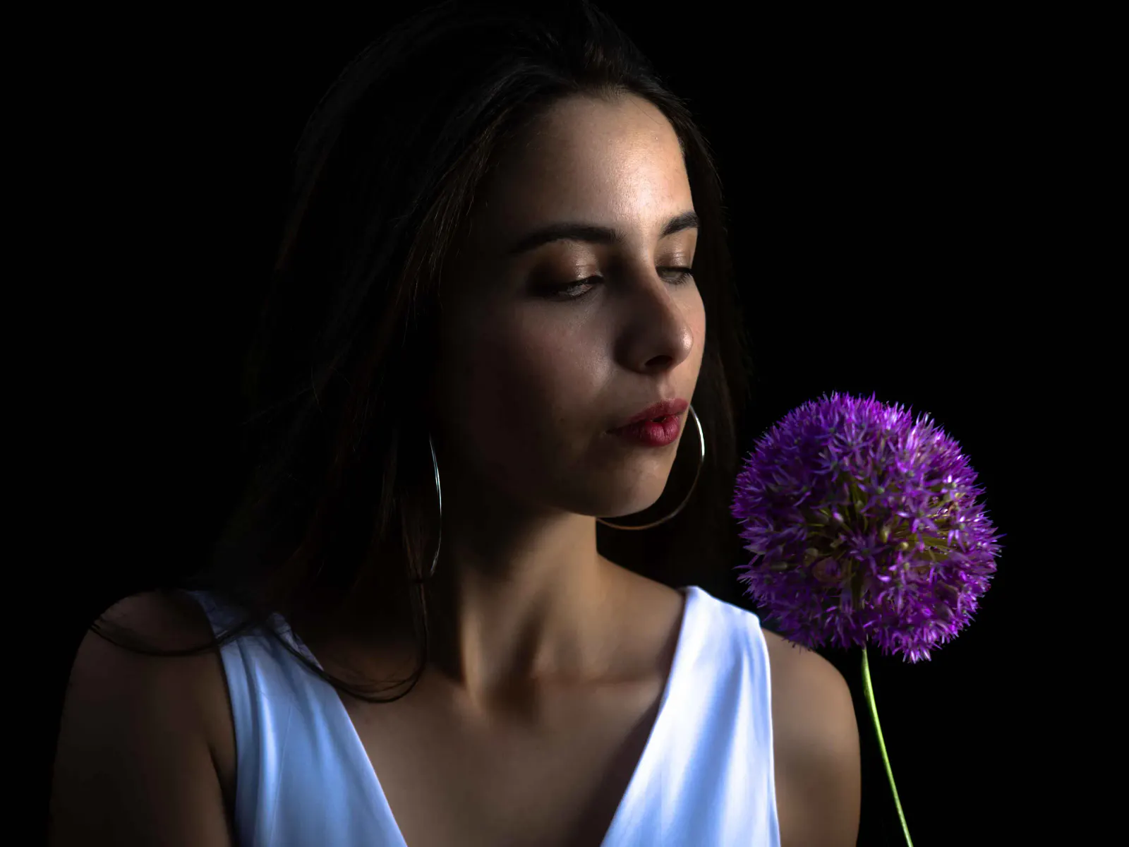 Frau mit violetter Blüte in einer dunkel inszenierten nächtlichen Portraitaufnahme.