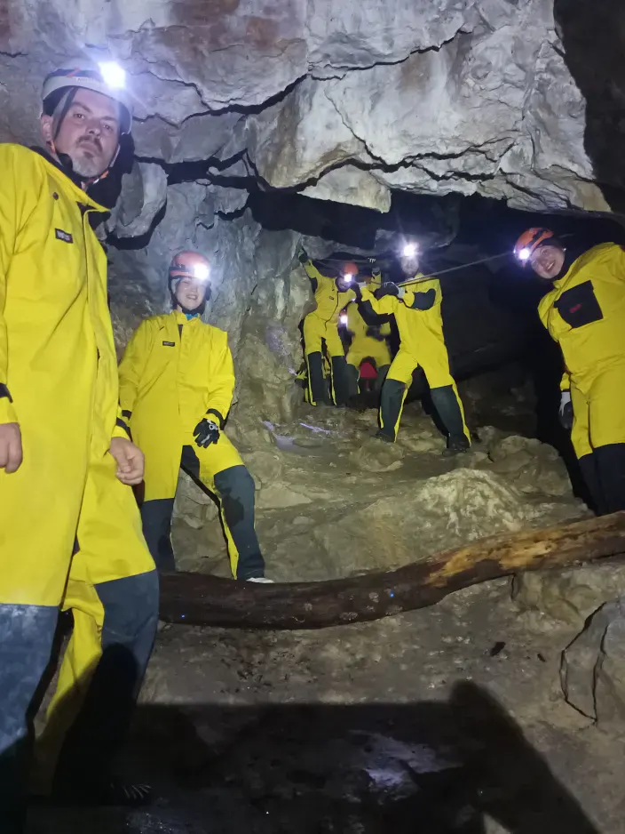 Mehrere Personen in Höhlenanzügen mit Helmen und Stirnlampen in der Höhle.