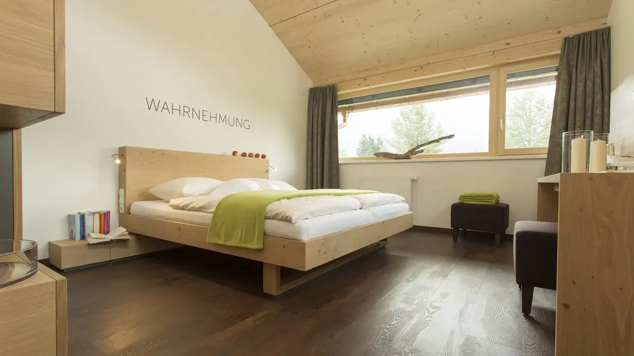 Modernes Doppelzimmer mit dem Schriftzug "Wahrnehmung" über dem Bett im Hotel Fischer am See ****