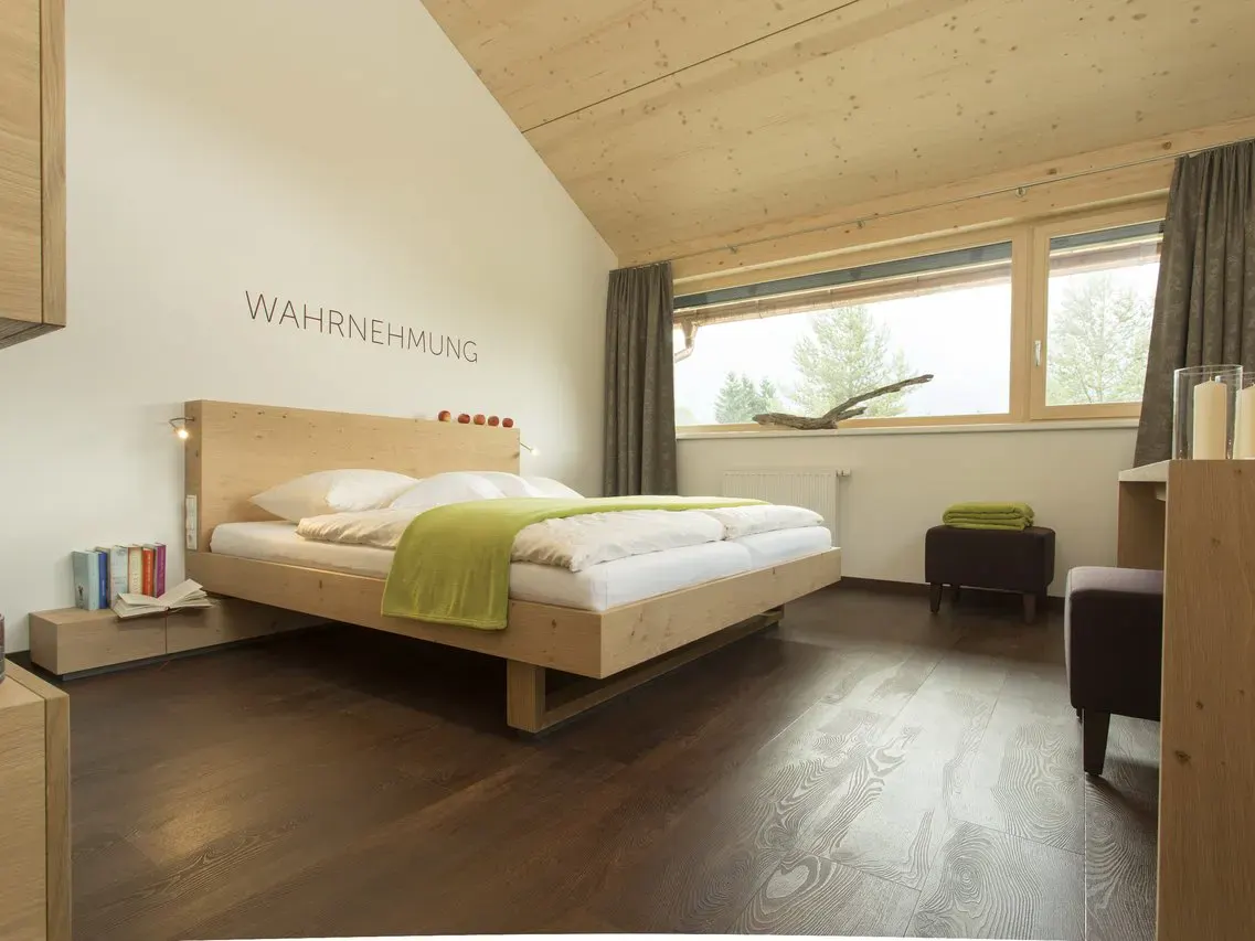 Modernes Doppelzimmer mit dem Schriftzug "Wahrnehmung" über dem Bett im Hotel Fischer am See ****