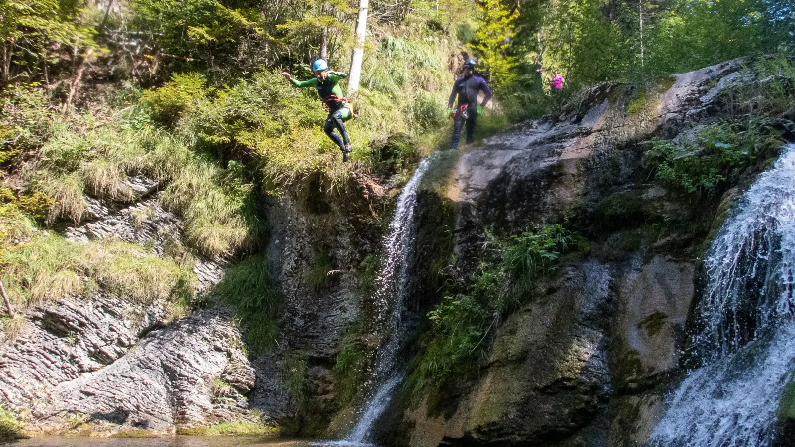 Eine Person in Neoprenanzug springt ins Wasser.