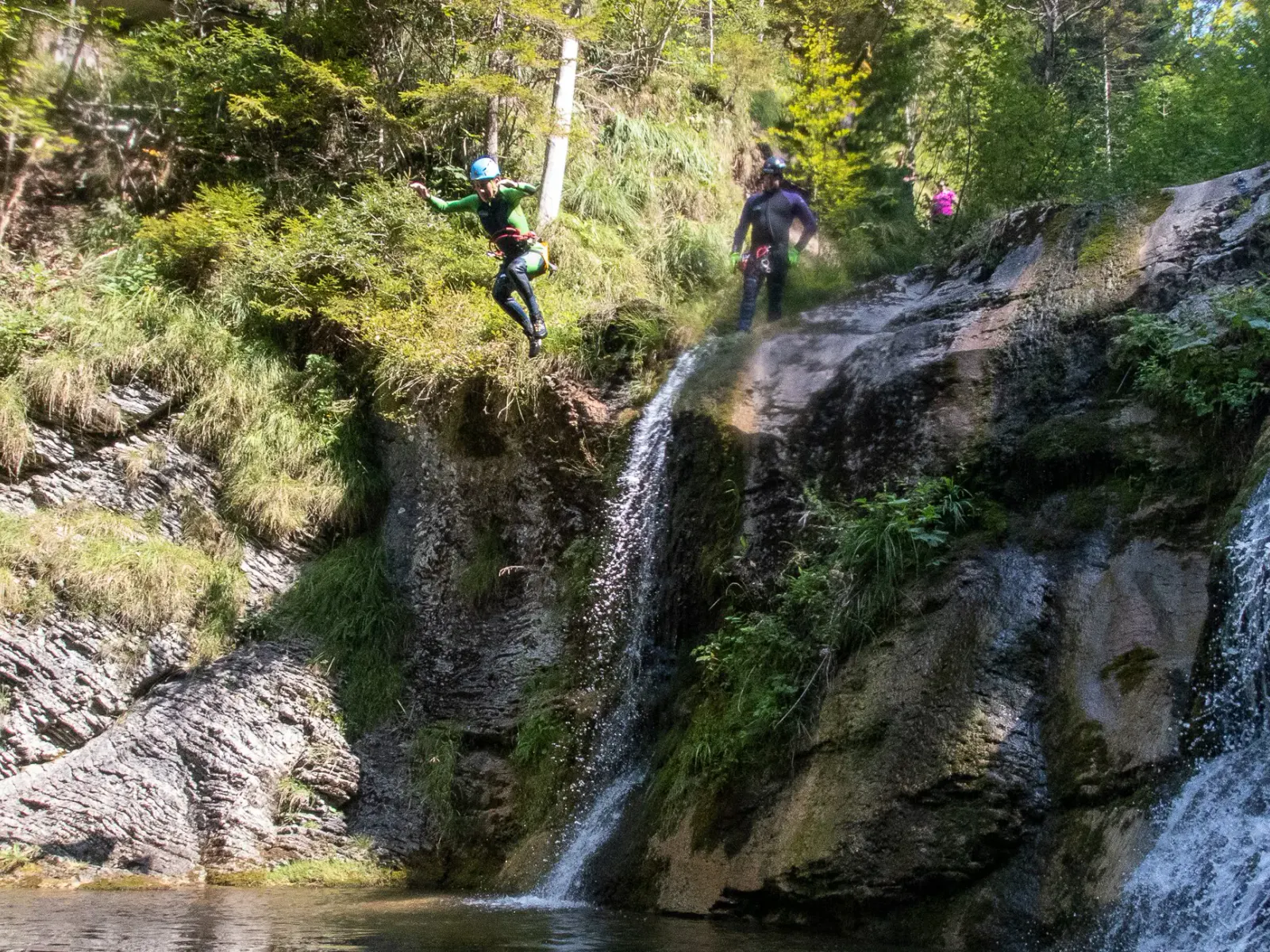 Eine Person in Neoprenanzug springt ins Wasser.
