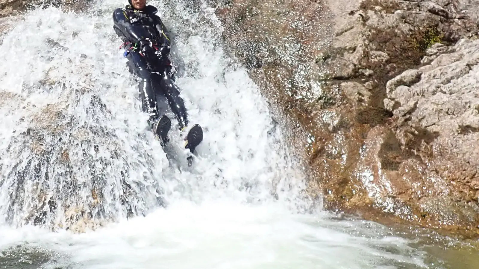 ein Canyonaut der einen Felsen hinunterrutscht