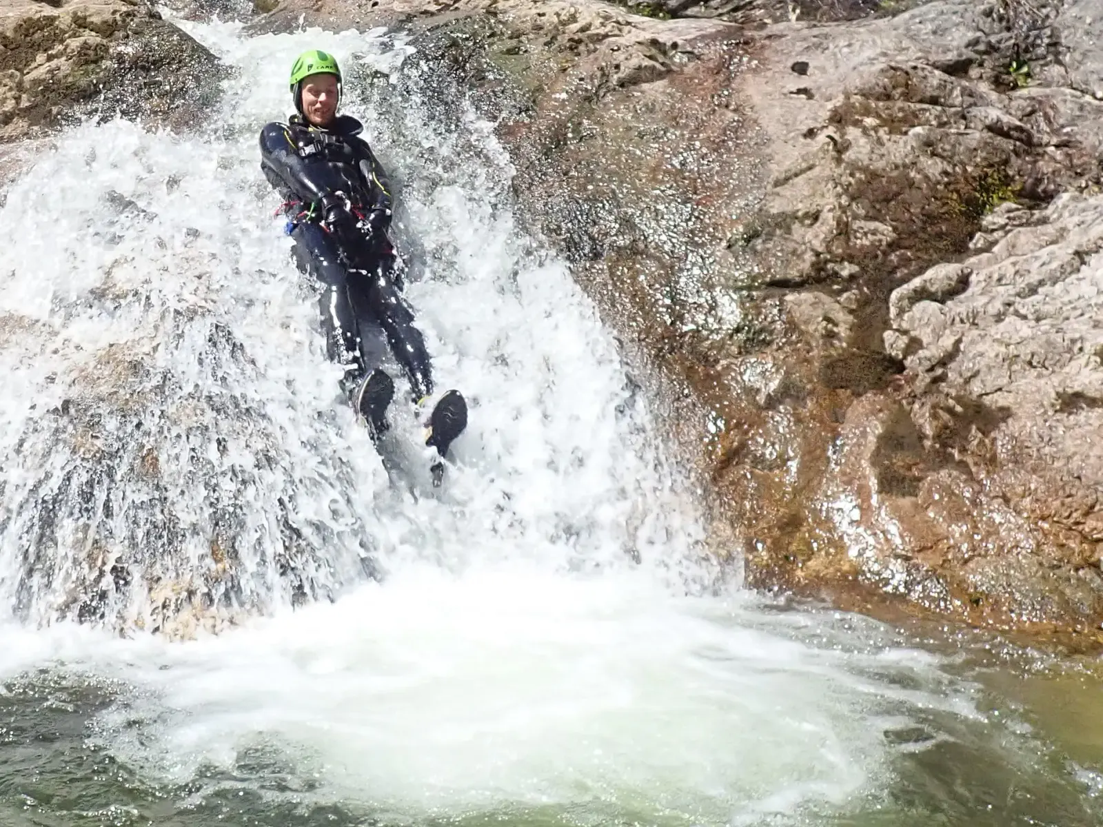 ein Canyonaut der einen Felsen hinunterrutscht