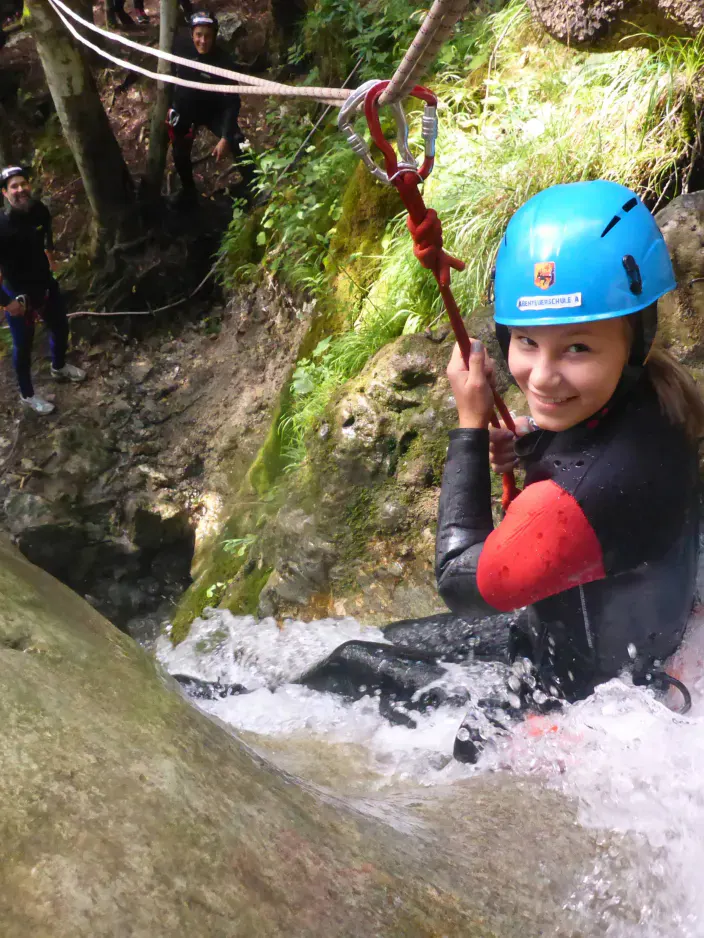Eine junge Canyonautin sind am Kopf eines Wasserfalls.