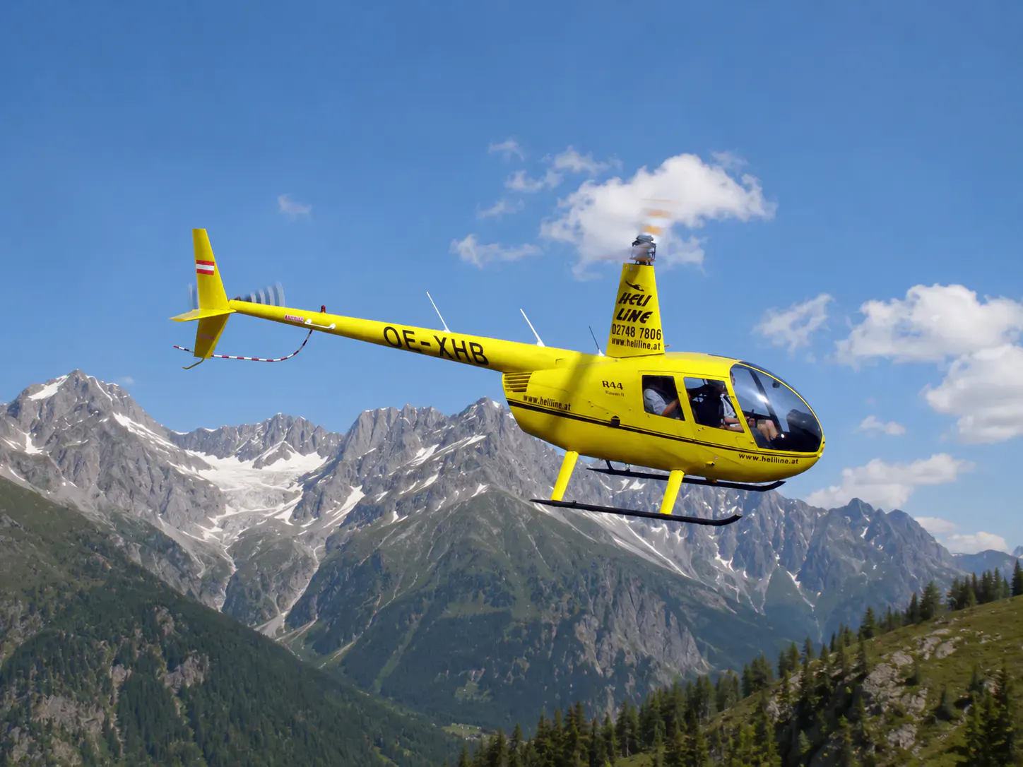 Helikopter in der Luft. Im Hintergund ein Berg.