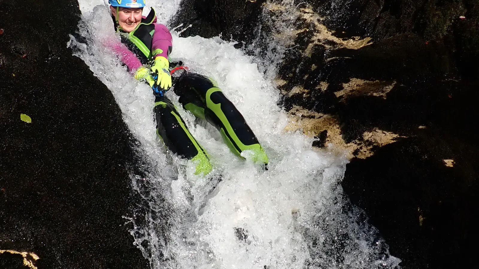 Eine Canyonautin rutscht in wildem Wasser.