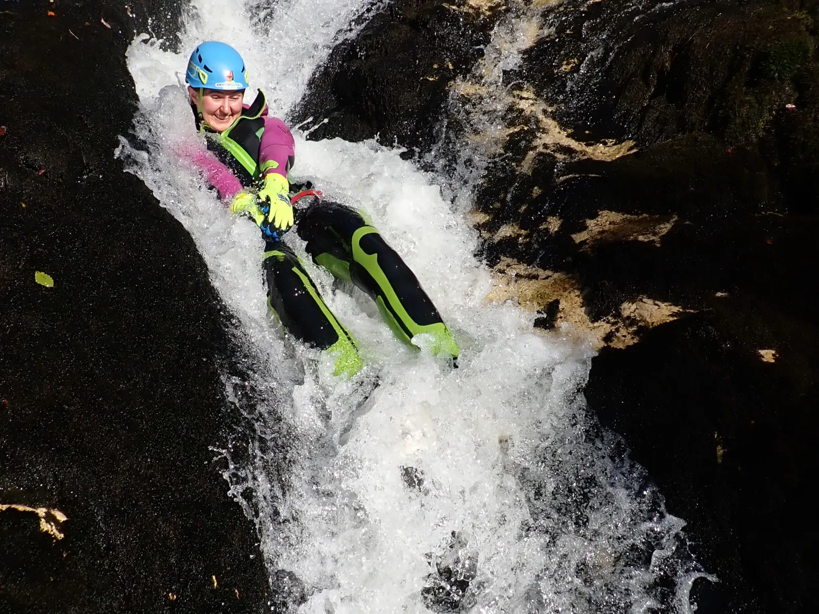 Eine Canyonautin rutscht in wildem Wasser.