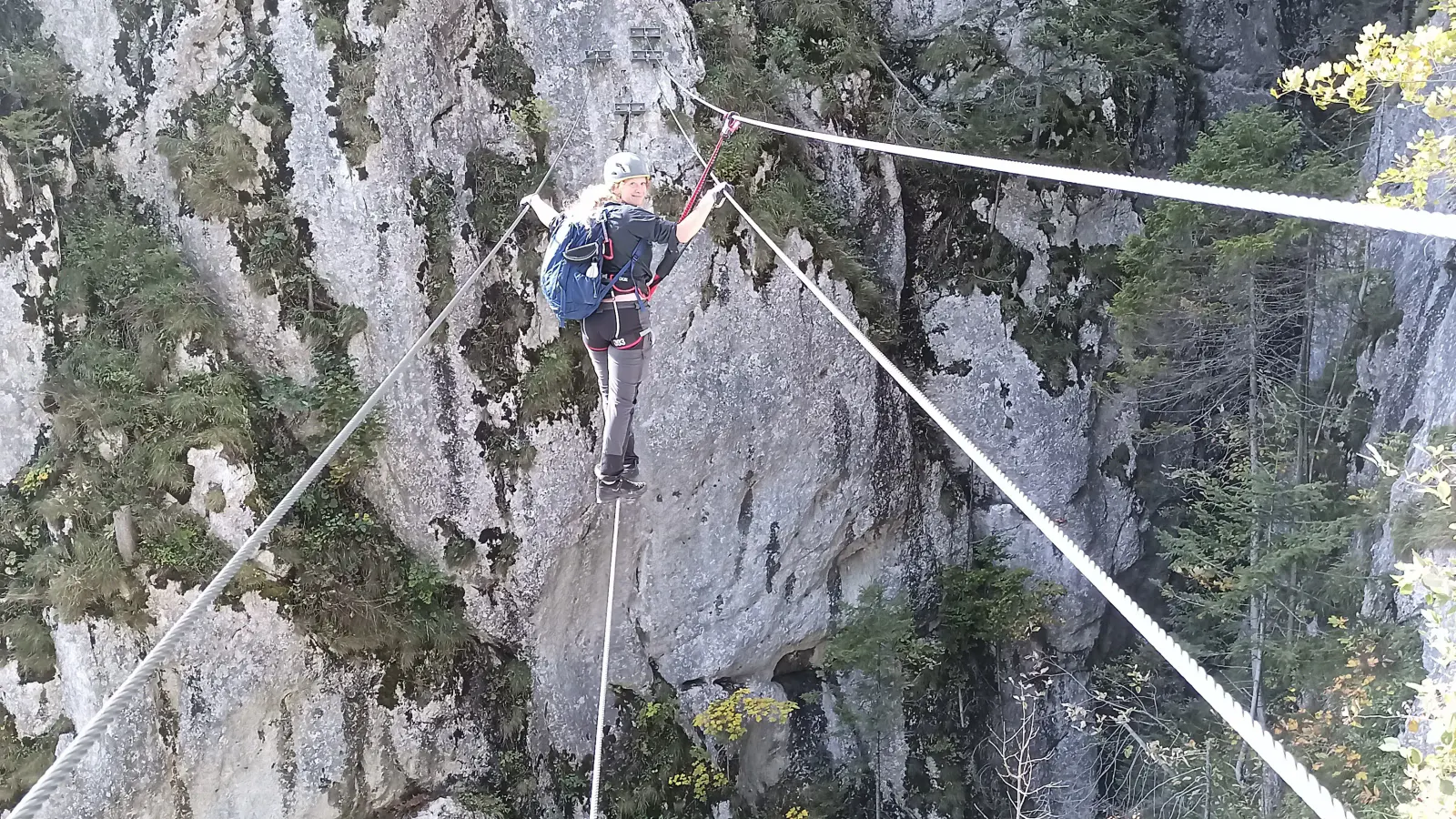 Eine Person balanciert auf einem Seil über eine Schlucht.