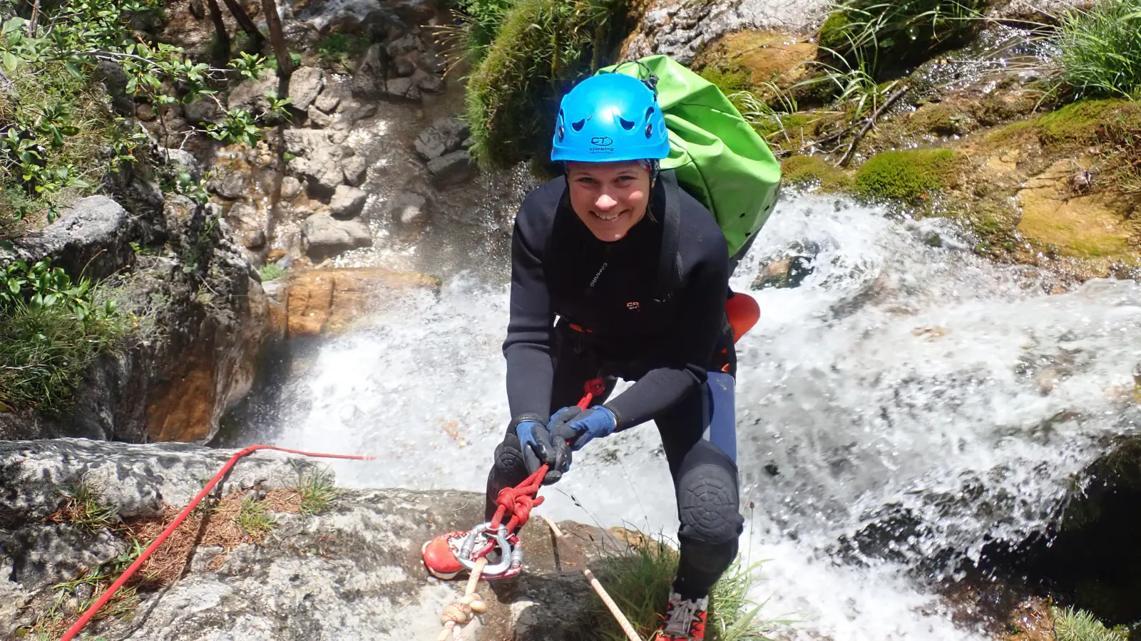 Eine Canyonautin wird beim Wasserfall abgeseilt.