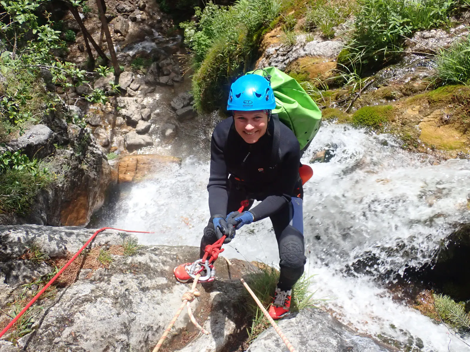 Eine Canyonautin wird beim Wasserfall abgeseilt.