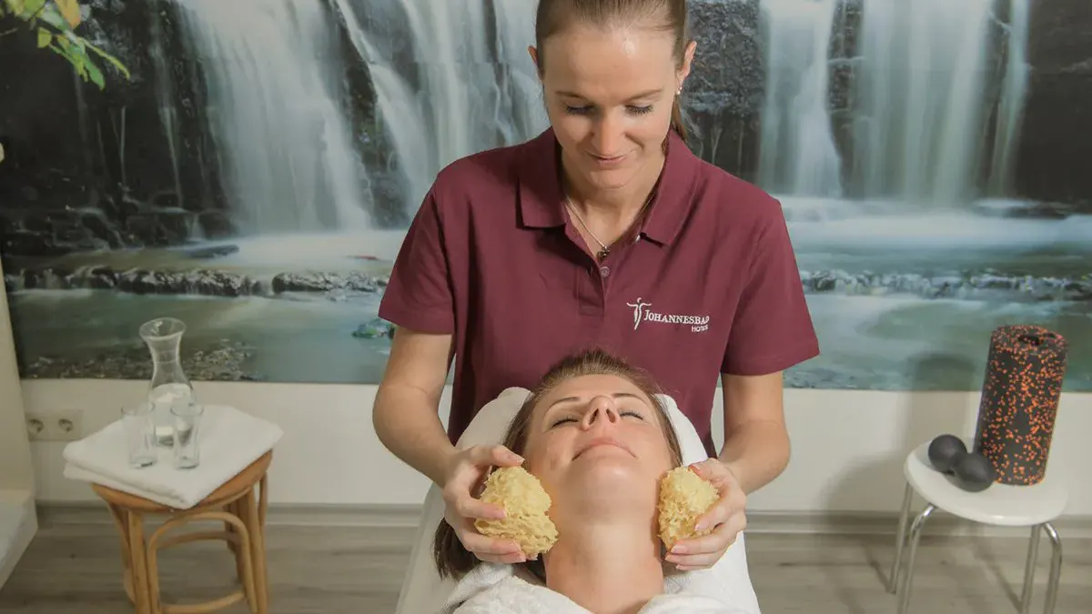 Eine Dame genießt eine Behandlung durch eine Therapeutin im Hotel Palace