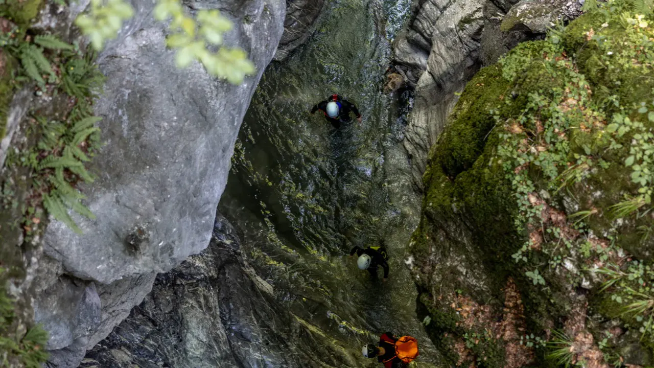 Draufsicht von oben auf Schlucht mit 3 Canyonauten im Wasser
