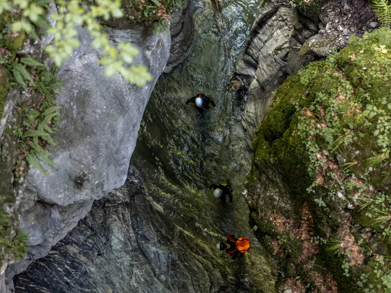 Draufsicht von oben auf Schlucht mit 3 Canyonauten im Wasser