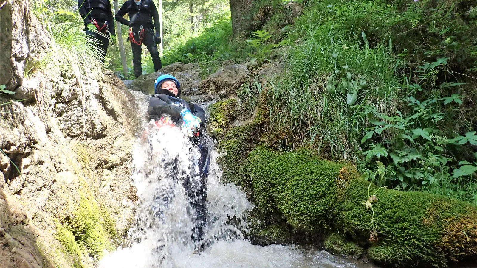 Eine Canyonautin rutscht durch eine Wasserfallstelle.