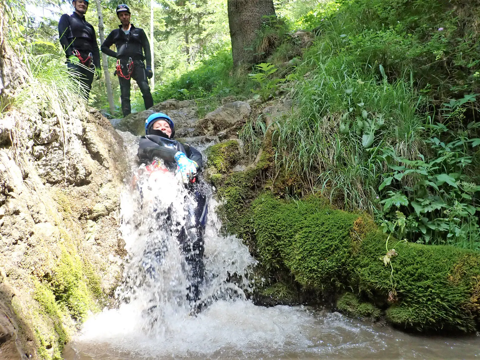 Eine Canyonautin rutscht durch eine Wasserfallstelle.