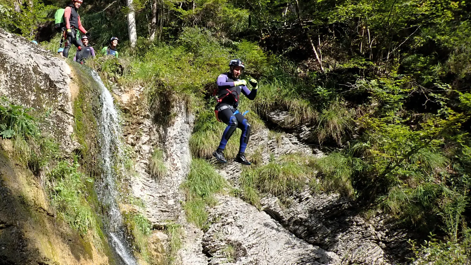 Eine Person in Canyoningausrüstung springt mehrere Meter ins Wasser.