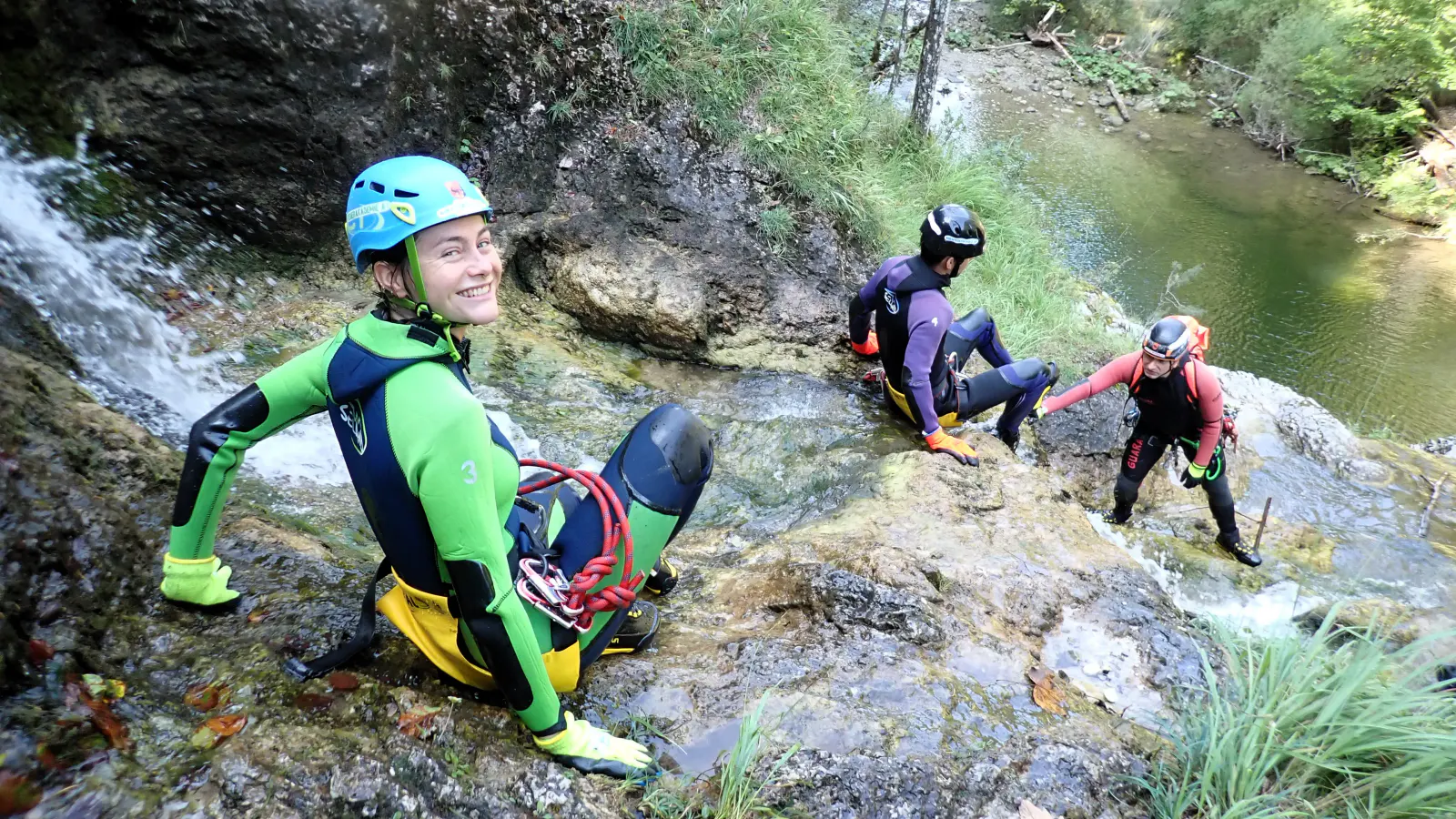 Mehrere Canyonaut:innen beim Abstieg über einen Fels