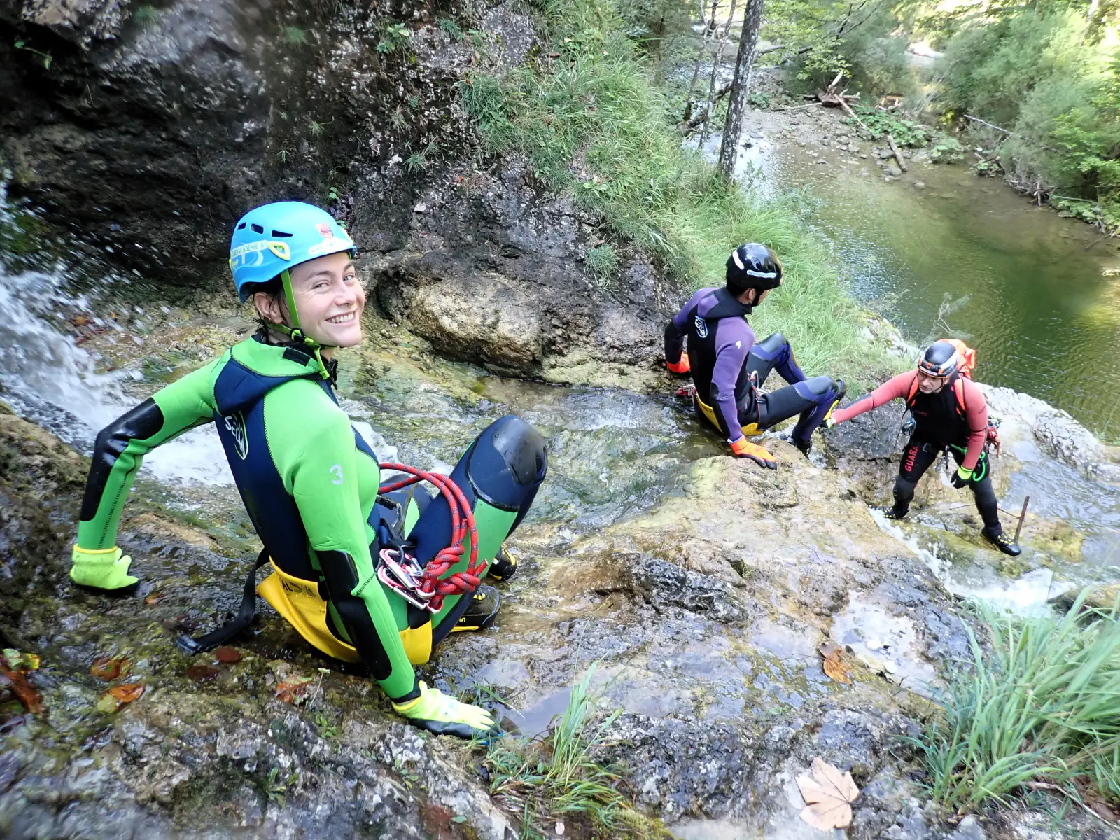 Mehrere Canyonaut:innen beim Abstieg über einen Fels
