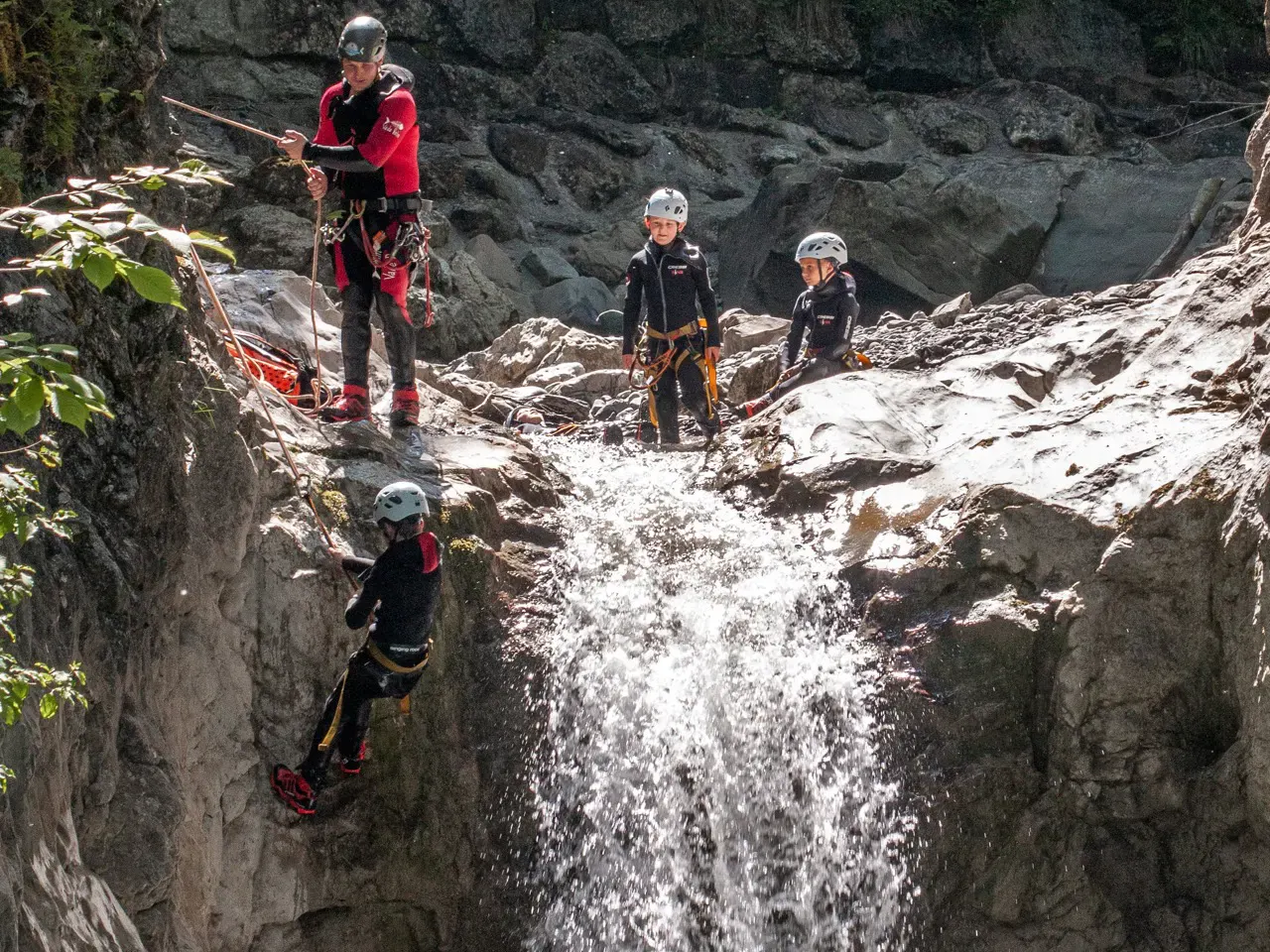 Kind wird von Guide neben Wasserfall abgeseilt