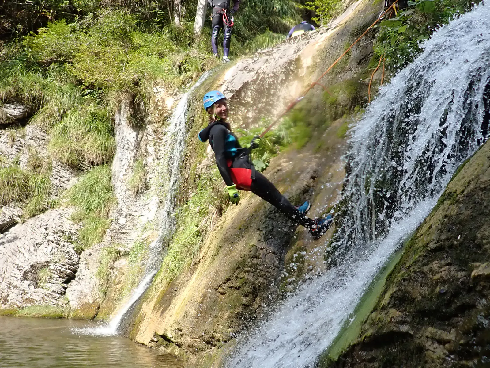 Eine Person wird neben einem Wasserfall abgeseilt.