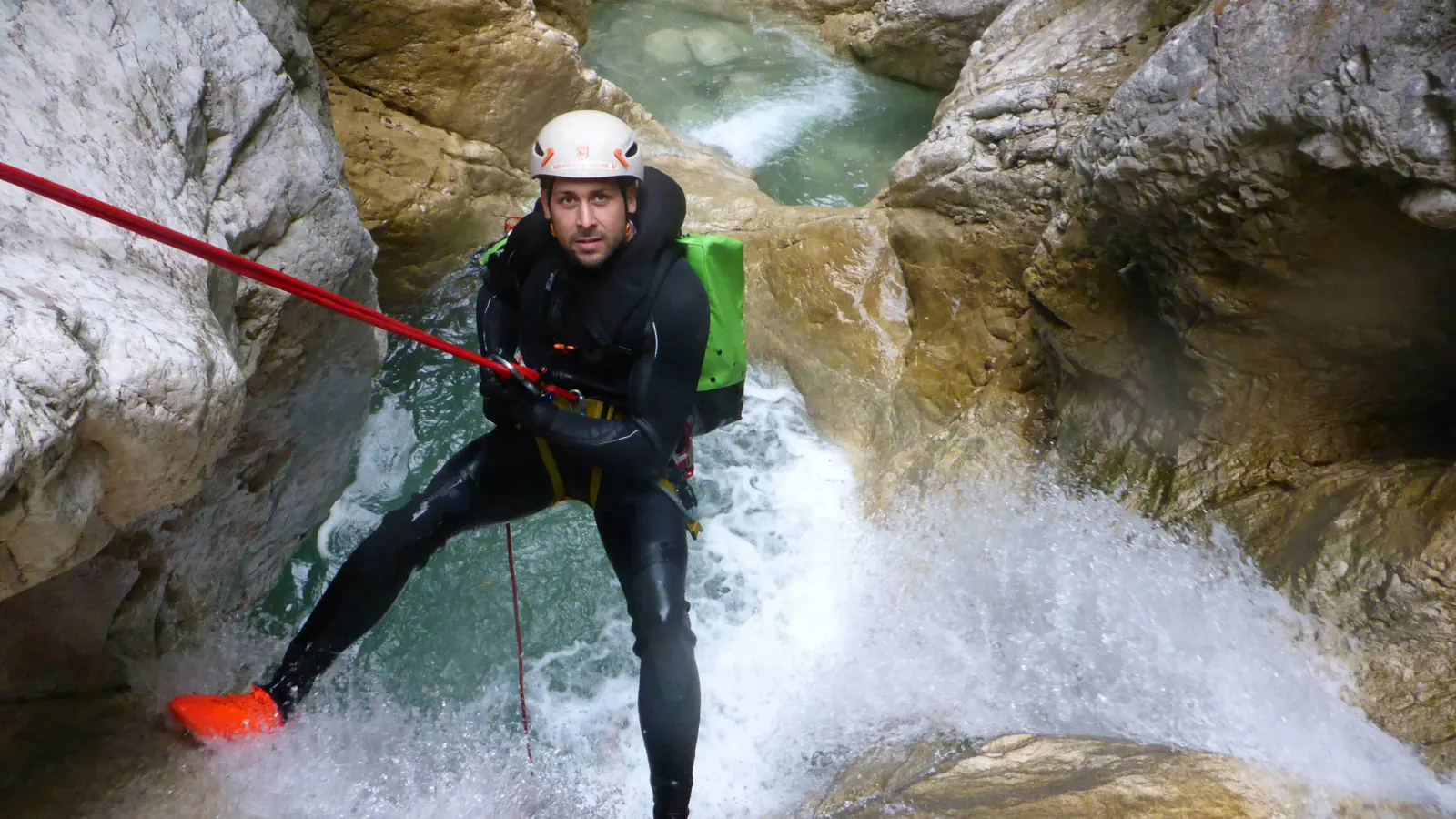 Ein Canyonaut seilt sich selbst in einem Wasserfall ab.