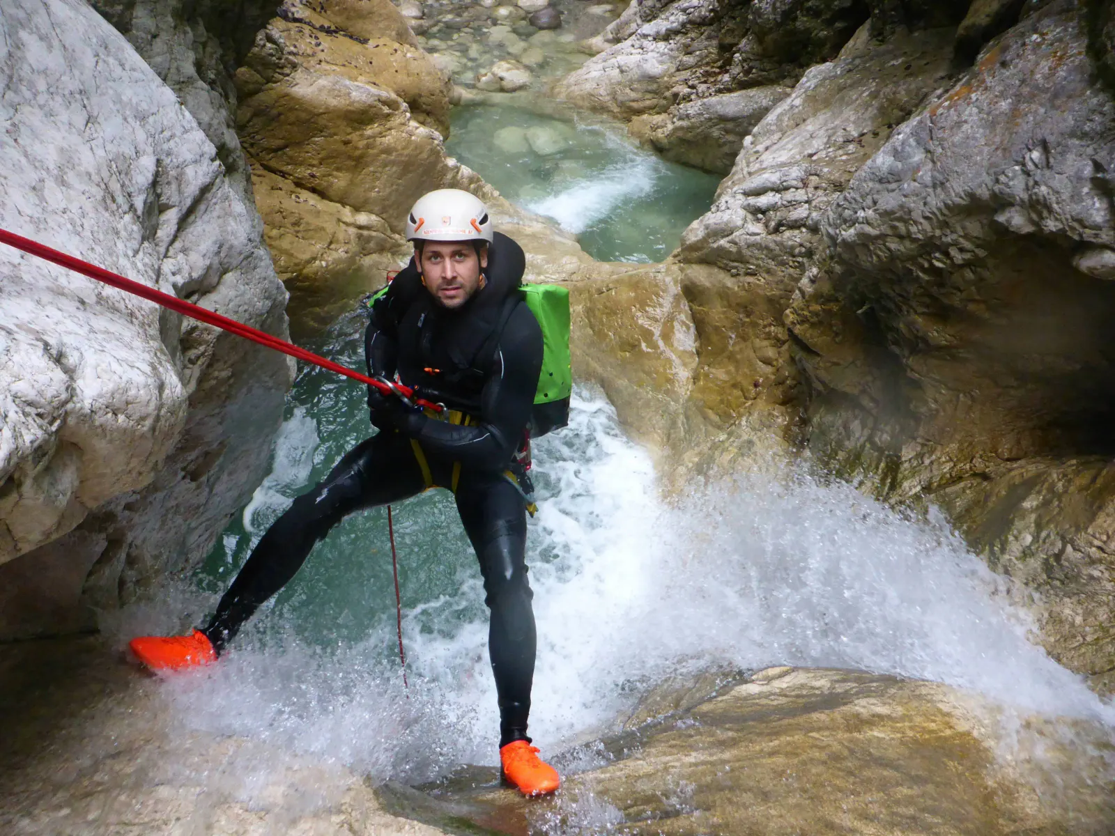 Ein Canyonaut seilt sich selbst in einem Wasserfall ab.