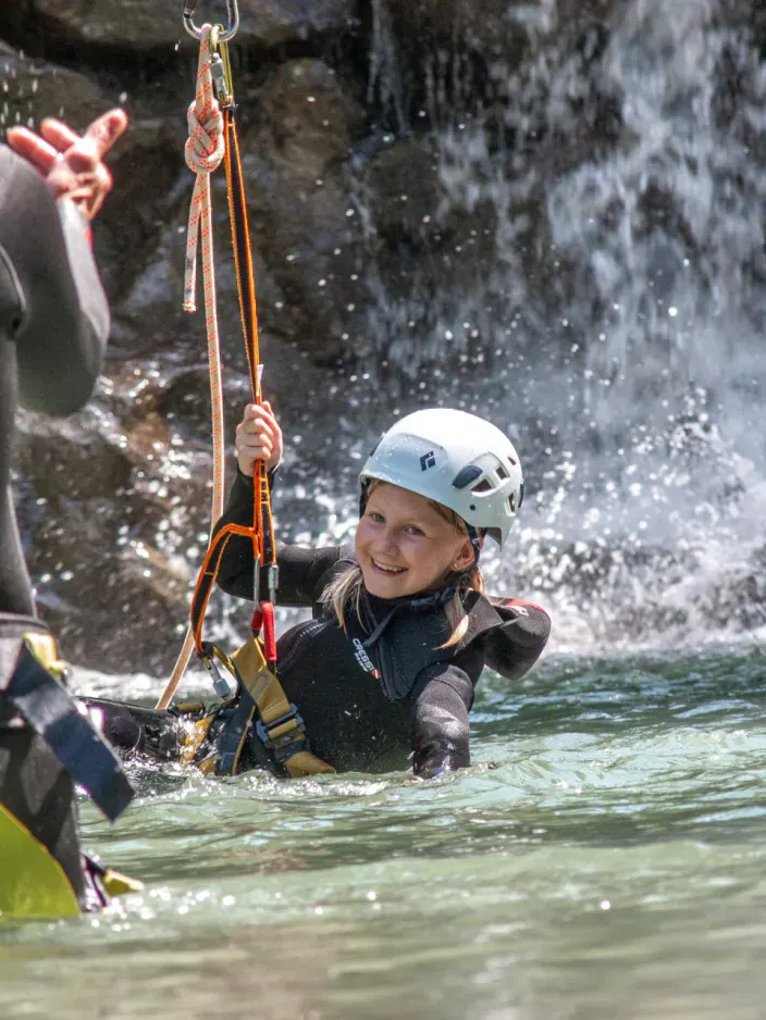 Mädchen lacht beim Eintauchen ins Wasser mit der Seilrutsche