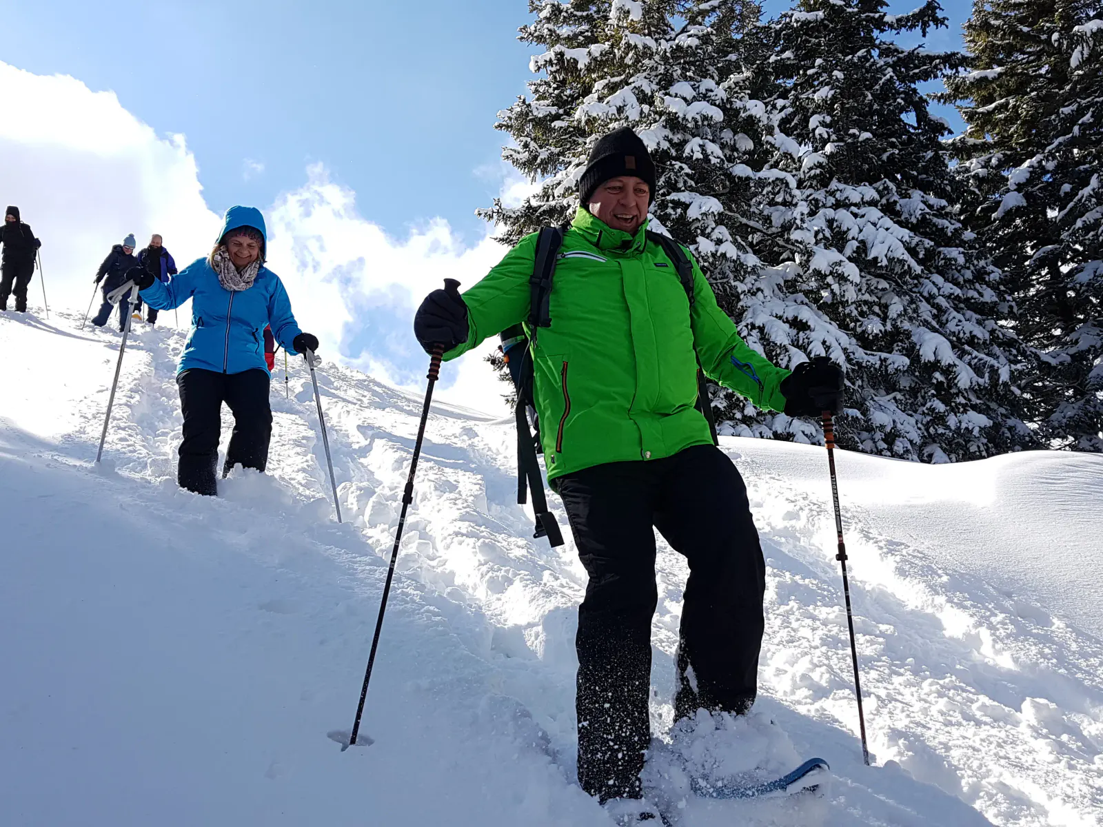 Personen, die lachend mit Schneeschuhen einen Hang hinunterlaufen.