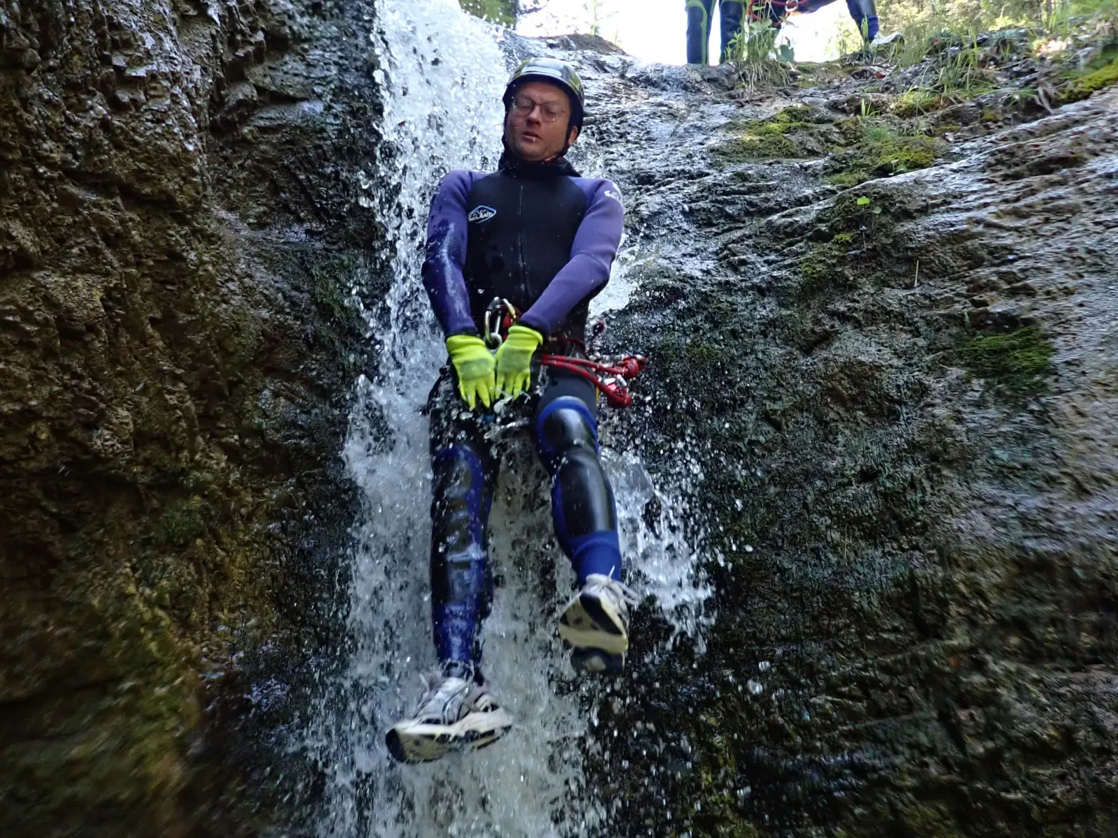 Eine Person rutscht einen kleinen Wasserfall hinunter.
