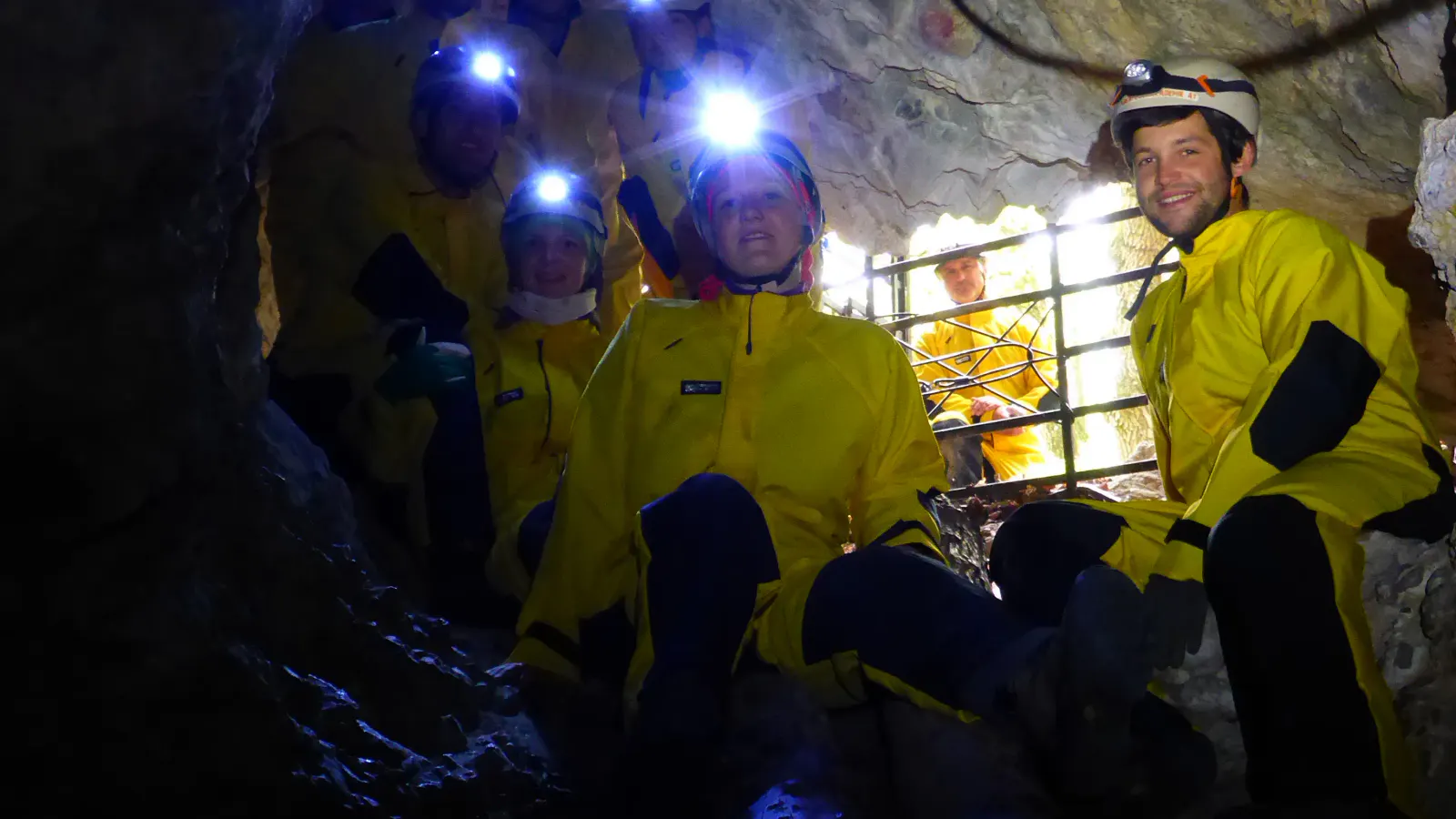 Personen in Höhlenanzügen mit Helmen und Stirnlampen in der Höhle