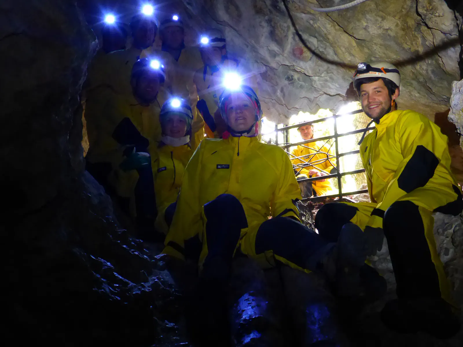 Personen in Höhlenanzügen mit Helmen und Stirnlampen in der Höhle