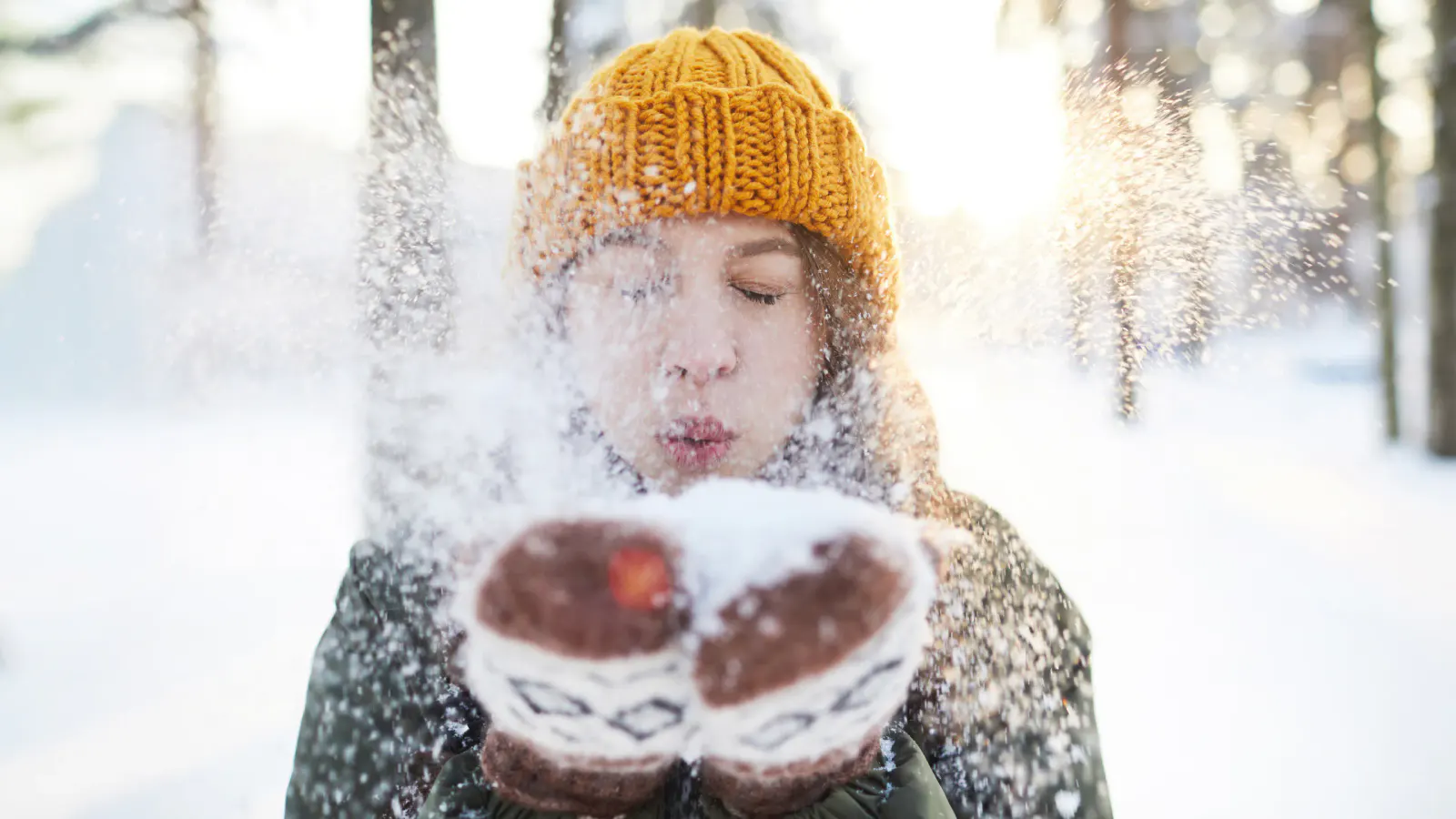 junge Frau haucht Schnee in die Kamera