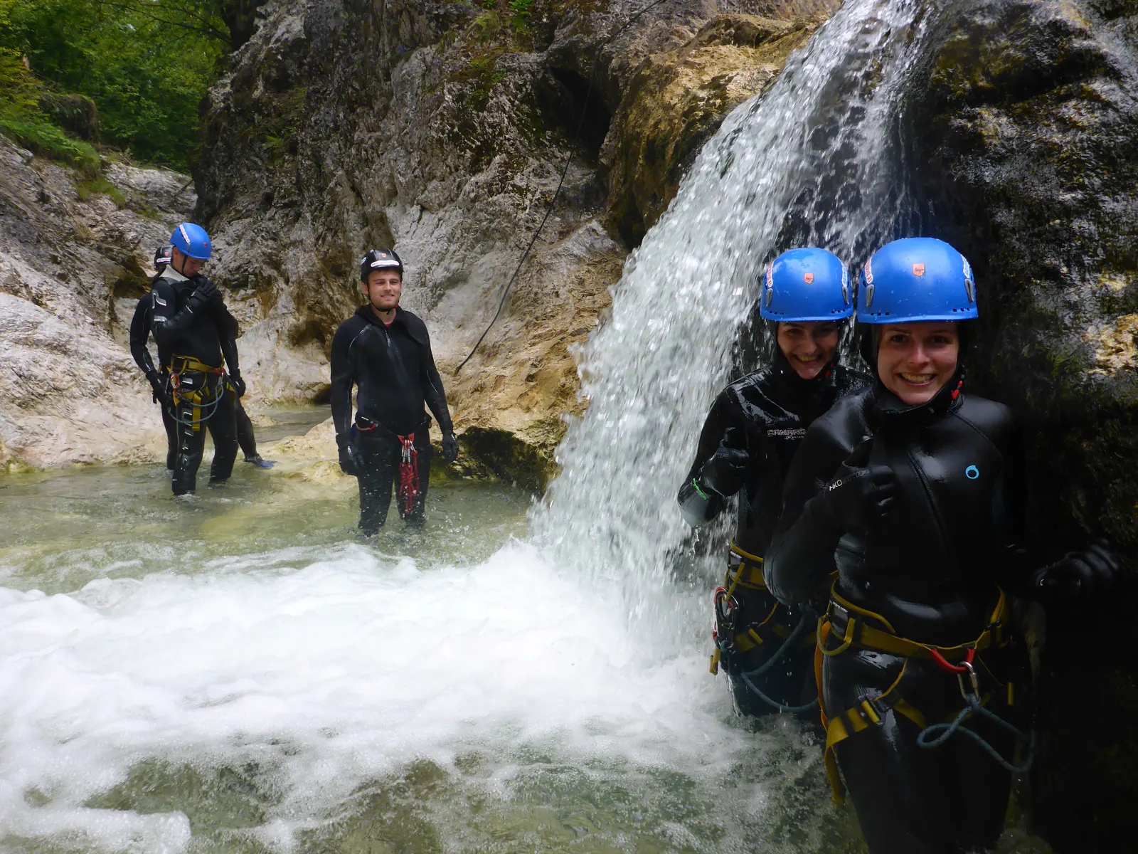 Canyonaut:innen beim Passieren einer Stelle mit tieferem Wasser und einem Wasserfall.