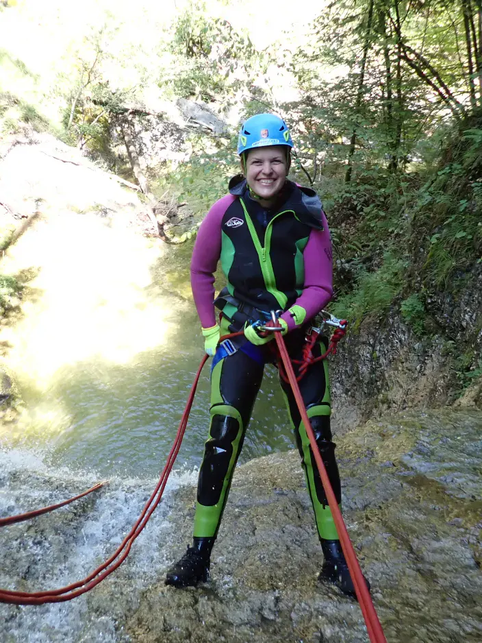 Eine Person bevor sie sich einen hohen Wasserfall abseilt.