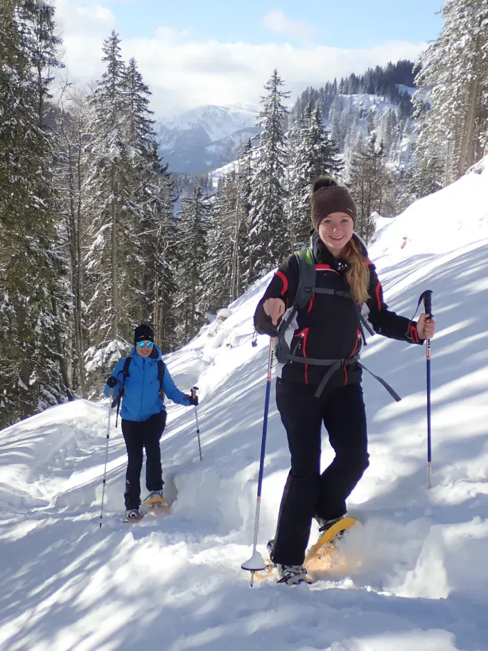 Zwei Personen wandern in einer weißen Winterlandschaft machen eine Schneeschuhwanderung