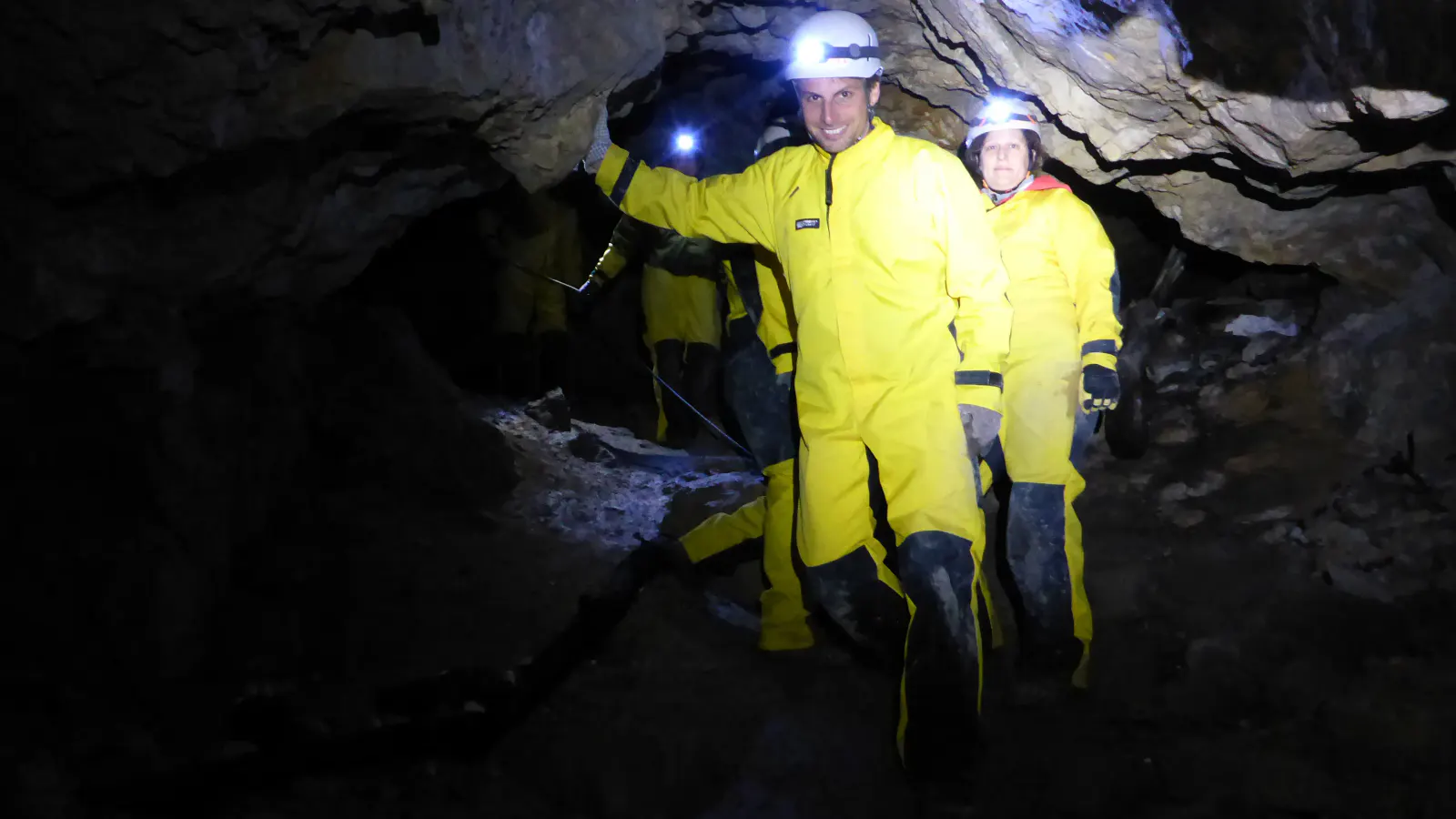 Personen in Höhlenanzügen gehen durch die Höhle