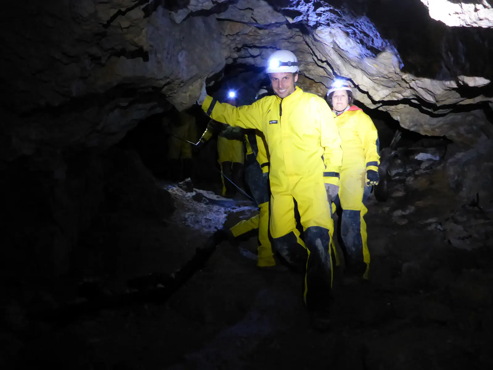 Personen in Höhlenanzügen gehen durch die Höhle