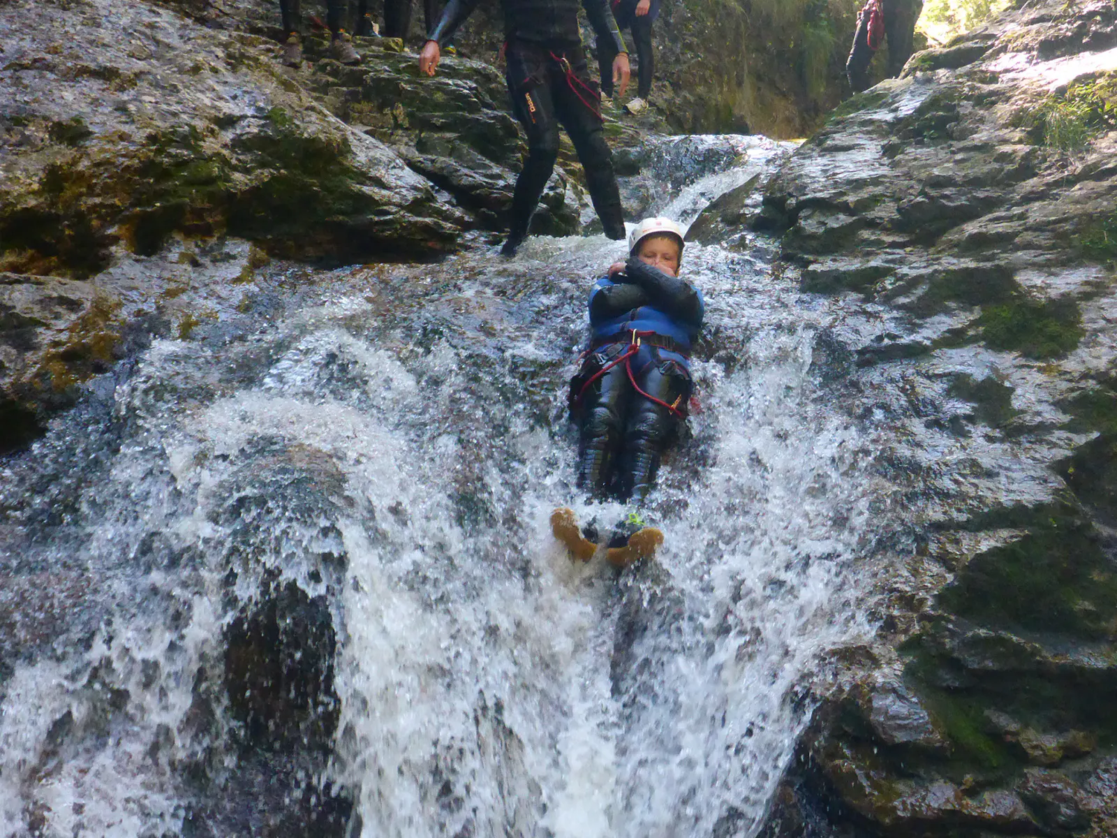 Eine junger Canyonaut, der einen Wasserfall hinunterrutscht.